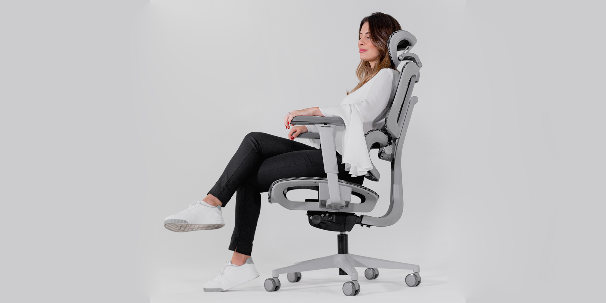 Modelo feminina utilizando uma cadeira modelo Sohpy em um fundo branco.