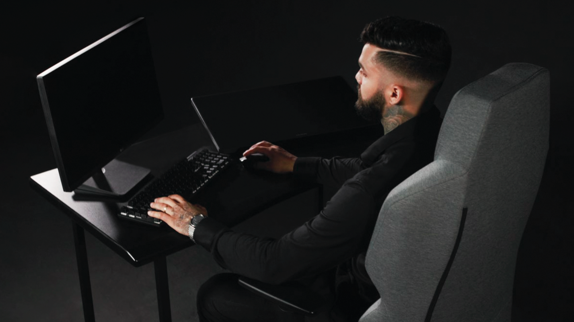 Homem no trabalho sentado em uma cadeira ergonomica e, aparentemente, seguindo orientações de ergonomia.