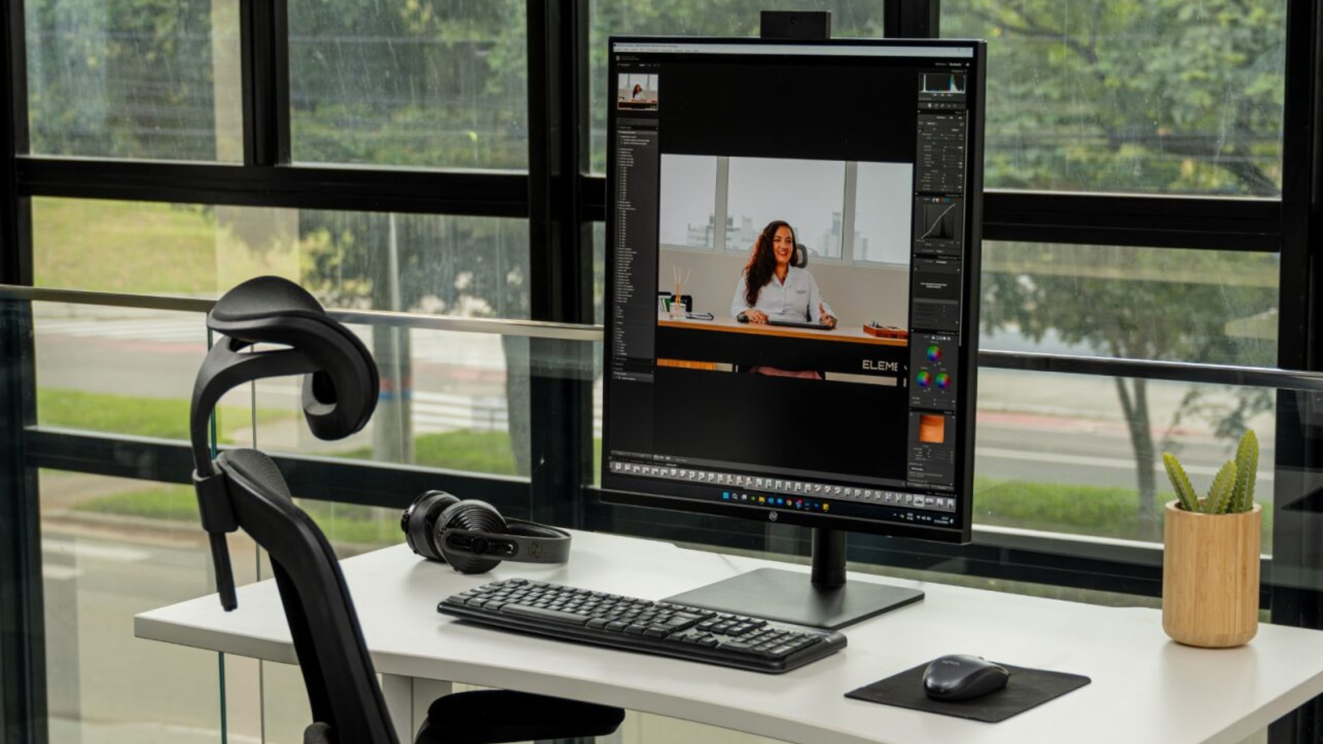 Setup de escritório com vídeo na tela de um monitor de fisioterapeuta ergonomista falando sobre ergonomia.