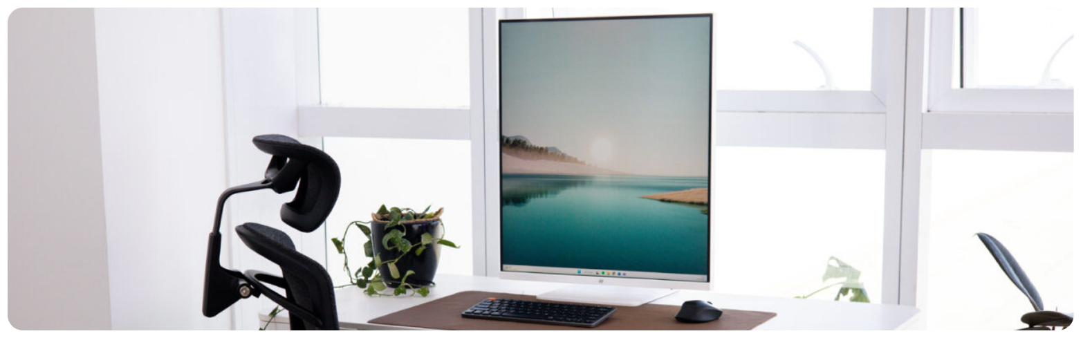 Fundo preto com um monitor vertical para designer em destaque. A tela mostra um nuvem cheia de cores.
