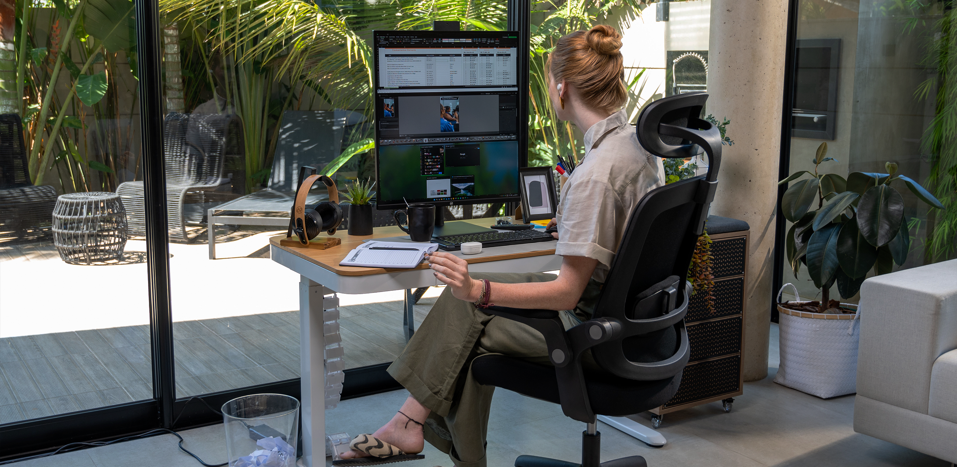 Mesa elétrica da cor branca e cadeira ergonômica preta com uma pessoa utilizando