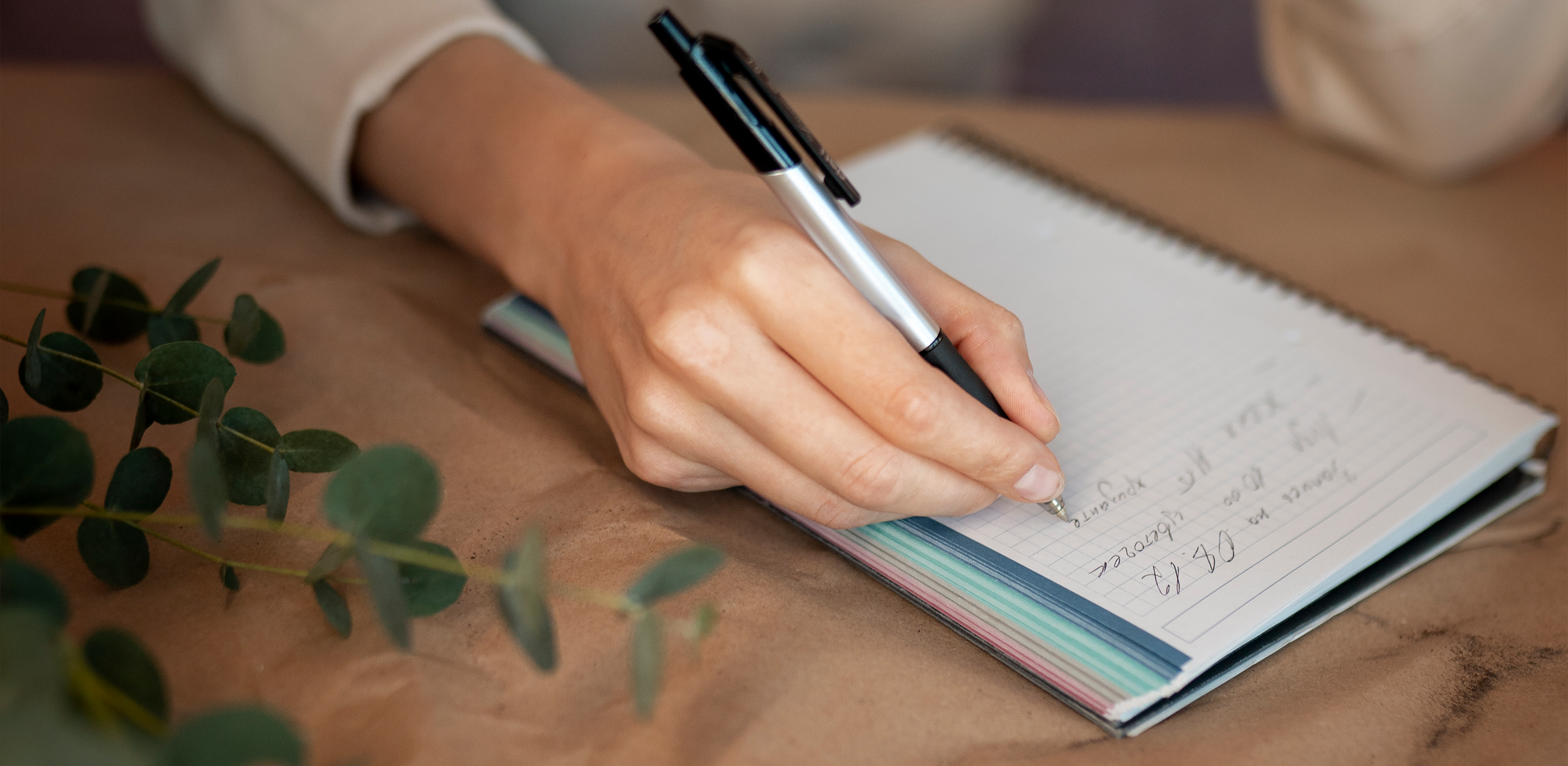 foto de uma mesa com um caderno e uma mão fazendo anotações