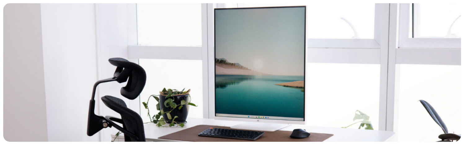 Fundo preto com um monitor vertical para designer em destaque. A tela mostra um nuvem cheia de cores.